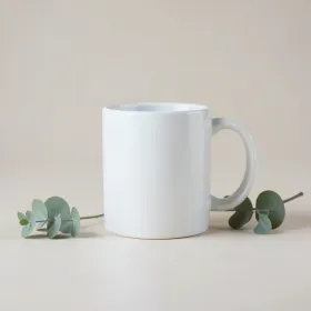 Clean product mockup of a plain blank white ceramic mug in soft studio light with a styling sprig