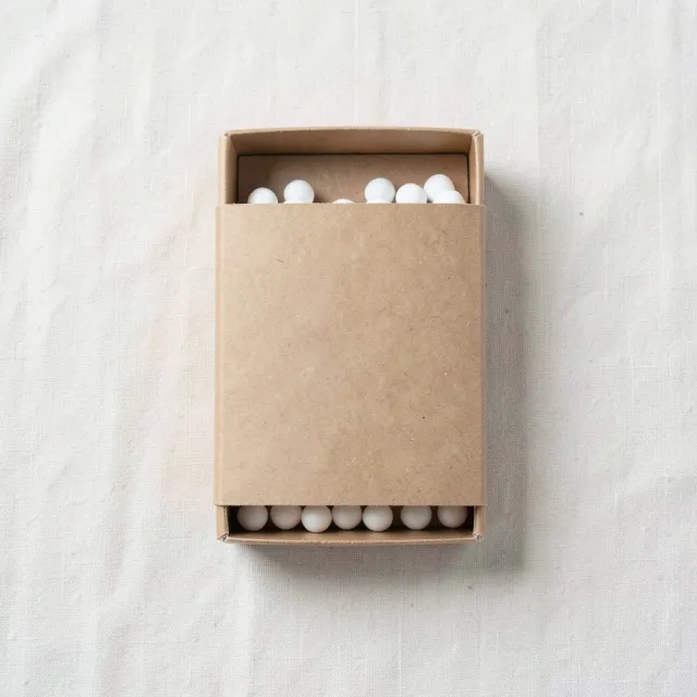 Blank unprinted kraft matchbox sleeve on pale linen, drawer slightly open, no lettering