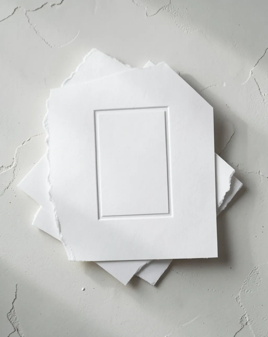 Stack of thick cotton letterpress cards with a blank blind-deboss panel, soft raking side light
