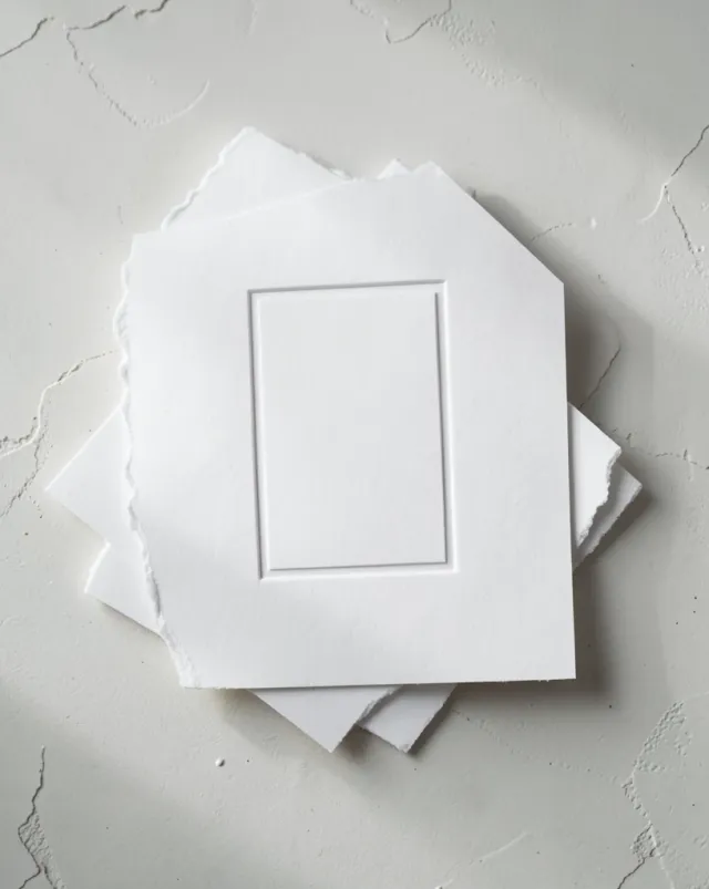 Stack of thick cotton letterpress cards with a blank blind-deboss panel, soft raking side light