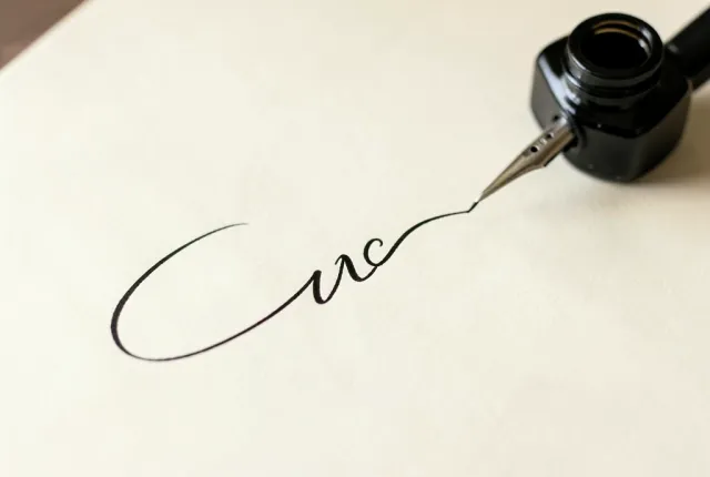 A pointed calligraphy nib flexing to lay a thick downstroke thinning to a hairline