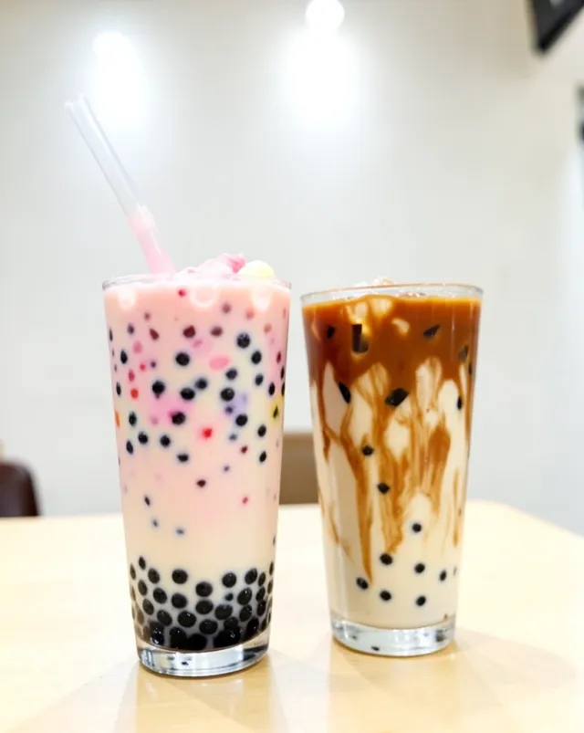 Tall glass of milk tea with brown sugar layers, cream, and black tapioca pearls with a wide straw
