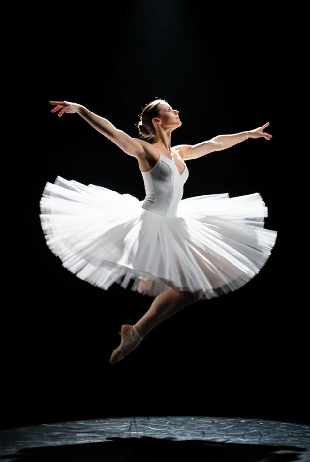 Dramatic ballerina mid-leap in flowing white tutu with rim light on a dark stage