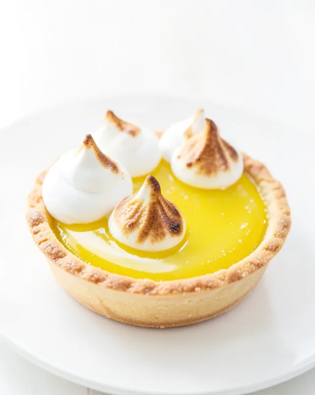 Lemon tart with glossy citrus curd, toasted golden meringue peaks, and thin pastry crust