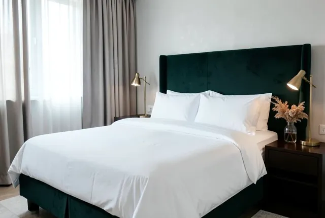 Luxury boutique hotel bedroom with white linens, velvet headboard, brass lamps, and soft natural light