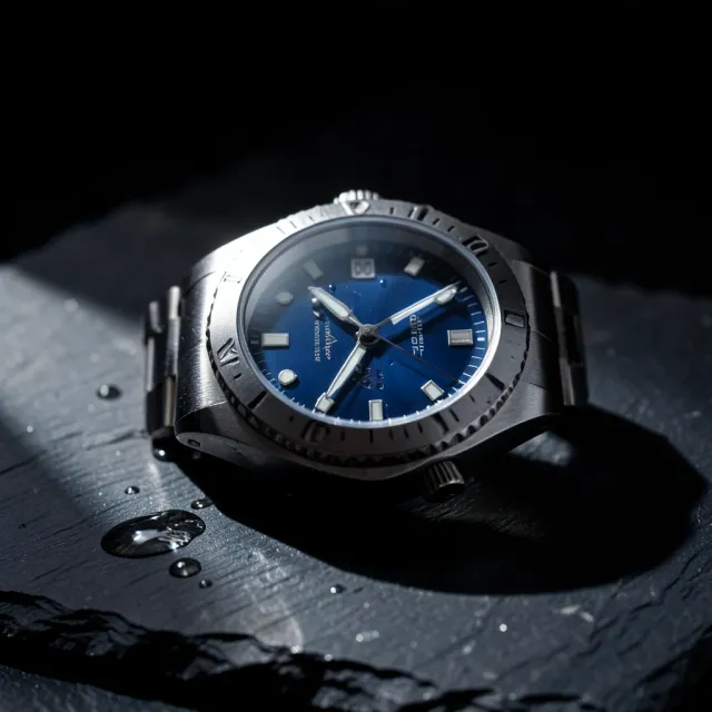 Luxury steel dive watch on wet dark slate under dramatic rim light with a rich blue dial