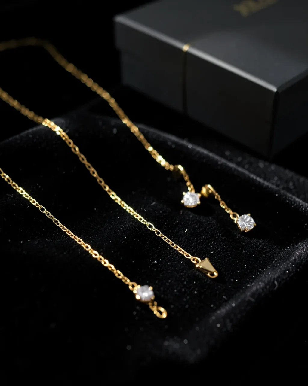 Luxury flat lay of a gold necklace and earrings on black velvet under soft directional studio light