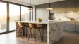 Modern kitchen island with marble countertop, wooden stools, pendant lights, and morning light through windows