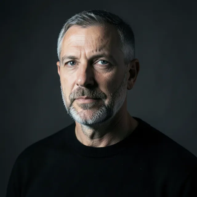A moody single-softbox studio headshot on charcoal