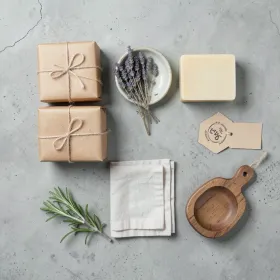 Product brand flatlay for handmade soap with kraft-wrapped bars lavender linen and rosemary on concrete