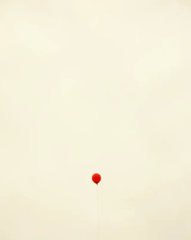 One small red balloon floating in a vast pale sky, minimalist Midjourney v7 render