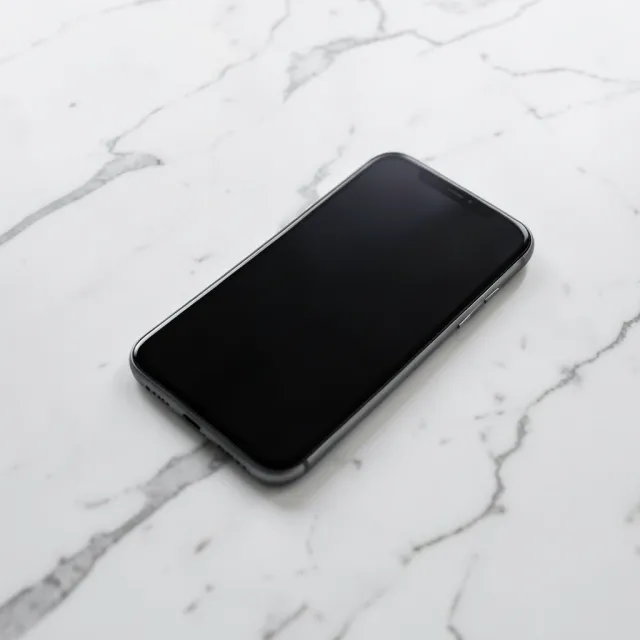Sleek modern smartphone lying flat on white marble with subtle grey veins and soft shadow