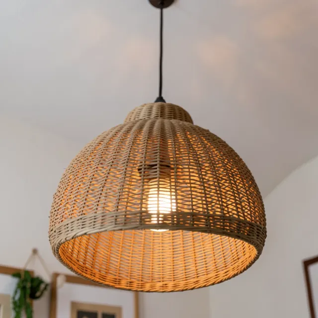 Close-up of a dome-shaped rattan pendant lamp with intricate weave glowing warmly against white ceiling